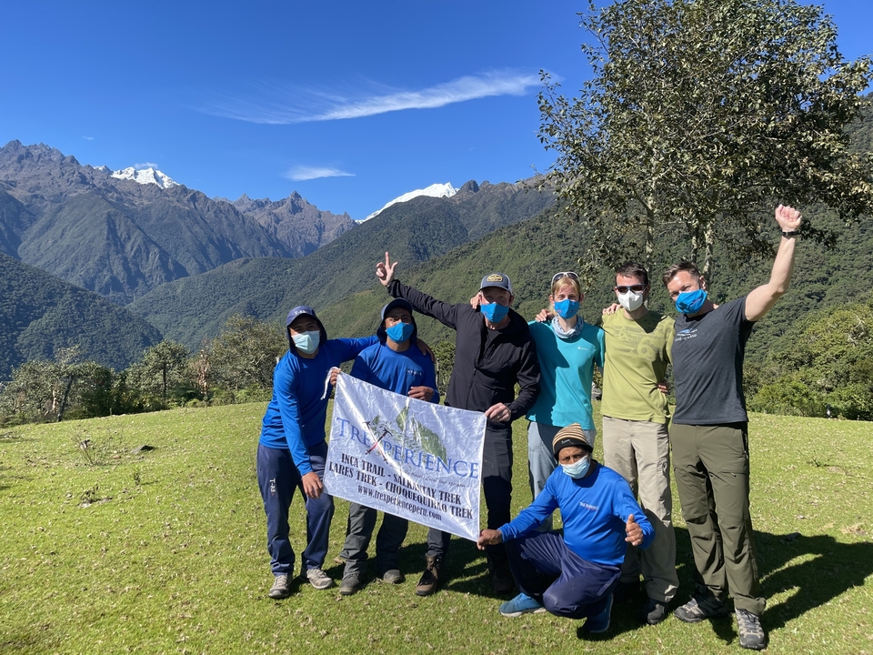 Group of people posing with a mountain backdrop, holding a banner.