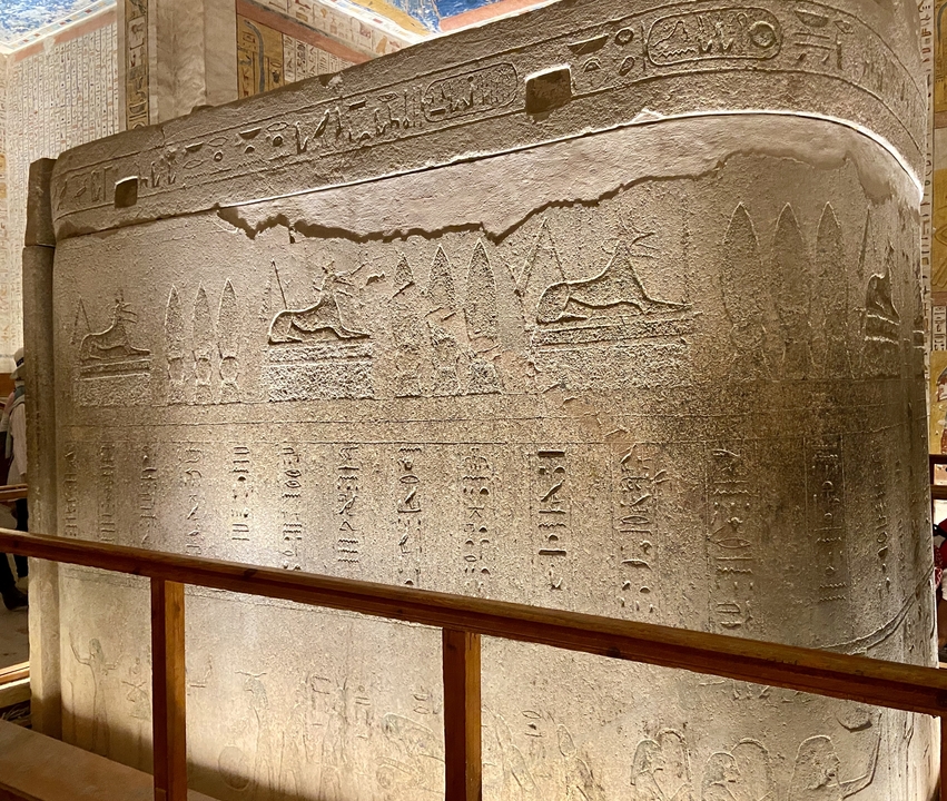 Close-up of a stone sarcophagus panel carved with jackals and hieroglyphs inside an Egyptian museum.