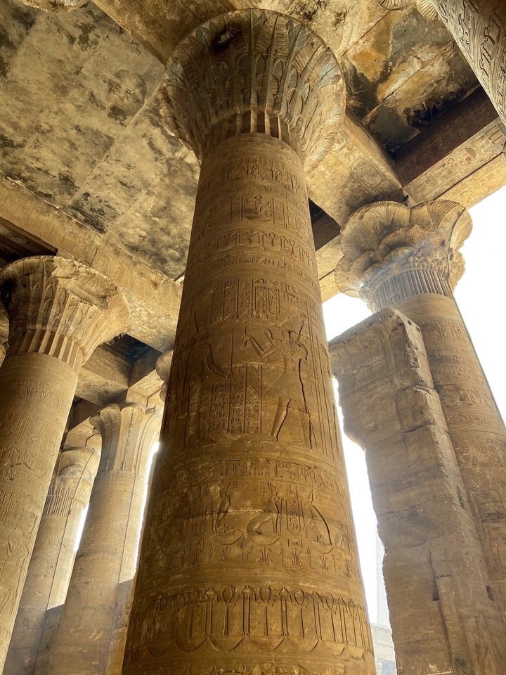 Close-up of massive sandstone columns covered in hieroglyphs inside an ancient Egyptian temple