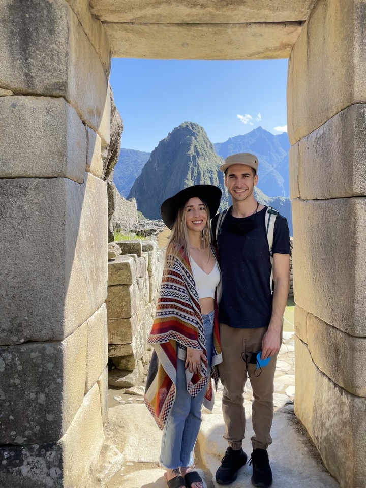 Two people posing in front of Machu Picchu with mountains in the background.