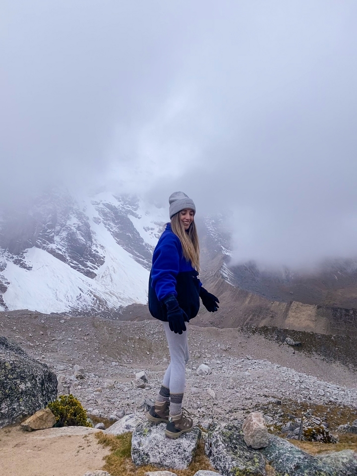 Person posing with snowcapped mountains in the background