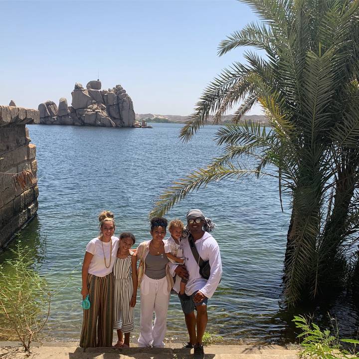 Family posing by the Nile with rocky formations.