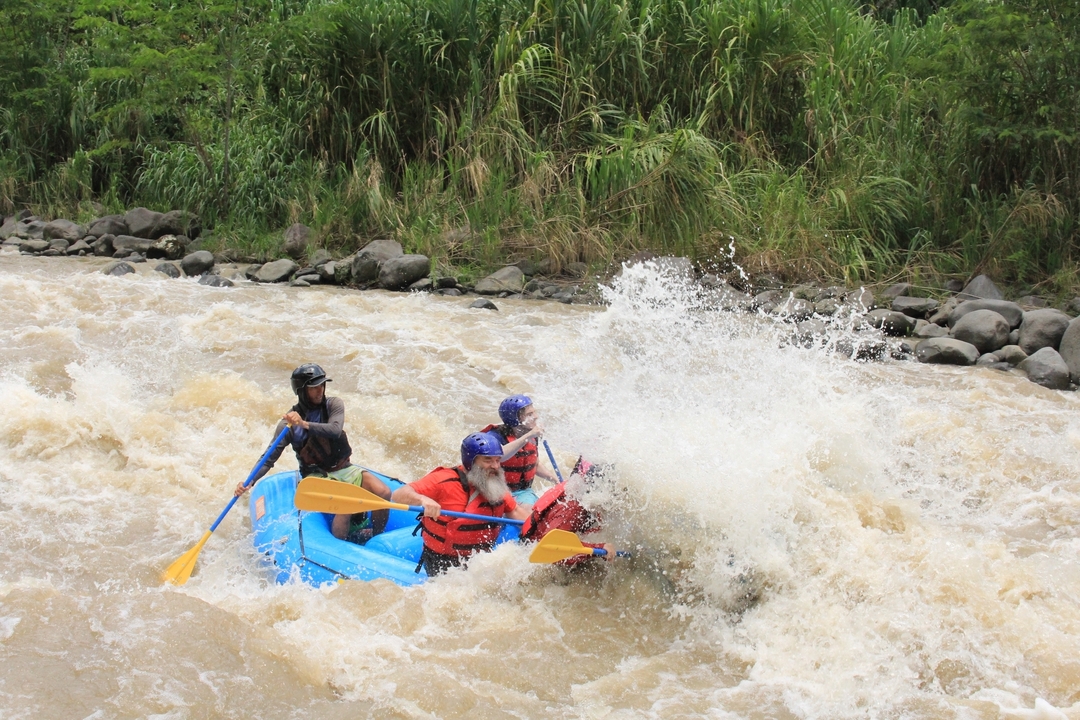 Rafting group caught mid-splash in a rapid river.