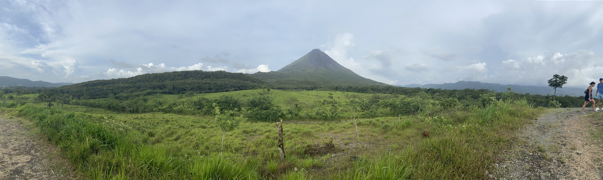 A distant volcano surrounded by green fields and hills.