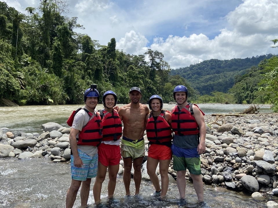 Group of people in life jackets by a river.