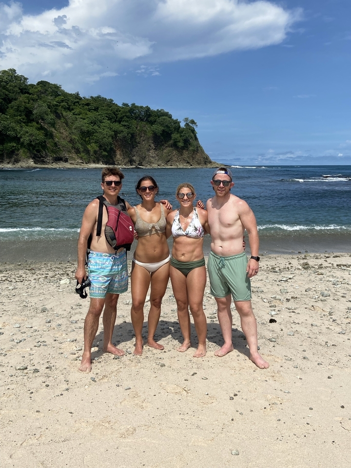 Group of people on a beach beneath high cliffs.
