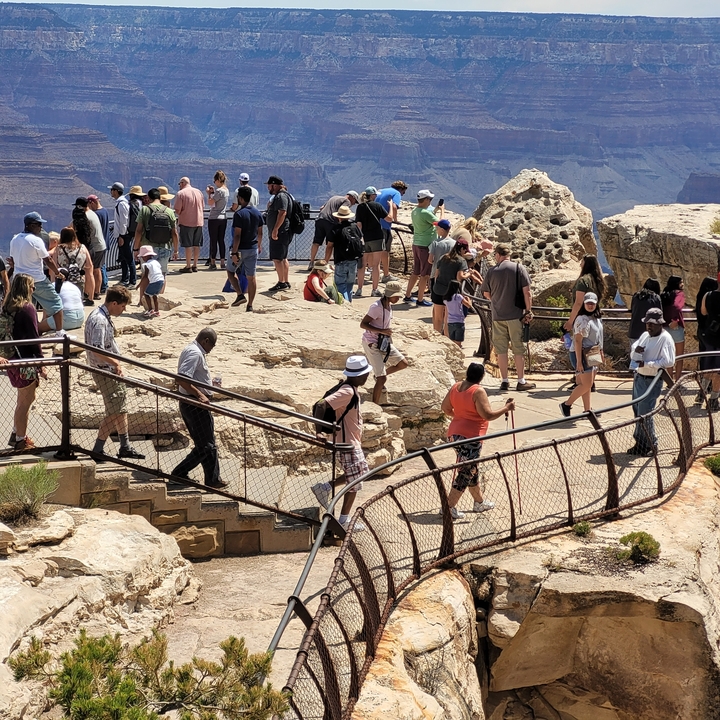Crowded observation deck with many tourists overlooking a canyon.