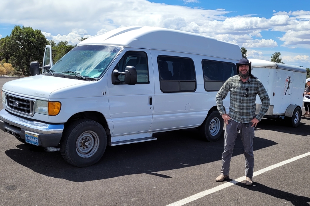 Person standing next to a white van in a parking area.