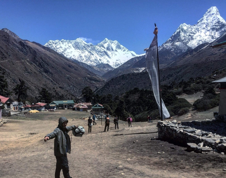 Group of trekkers in a mountain village with snowy peaks.