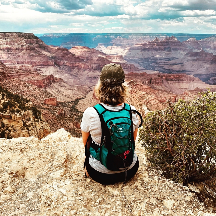 Person sitting on the edge overlooking a canyon.