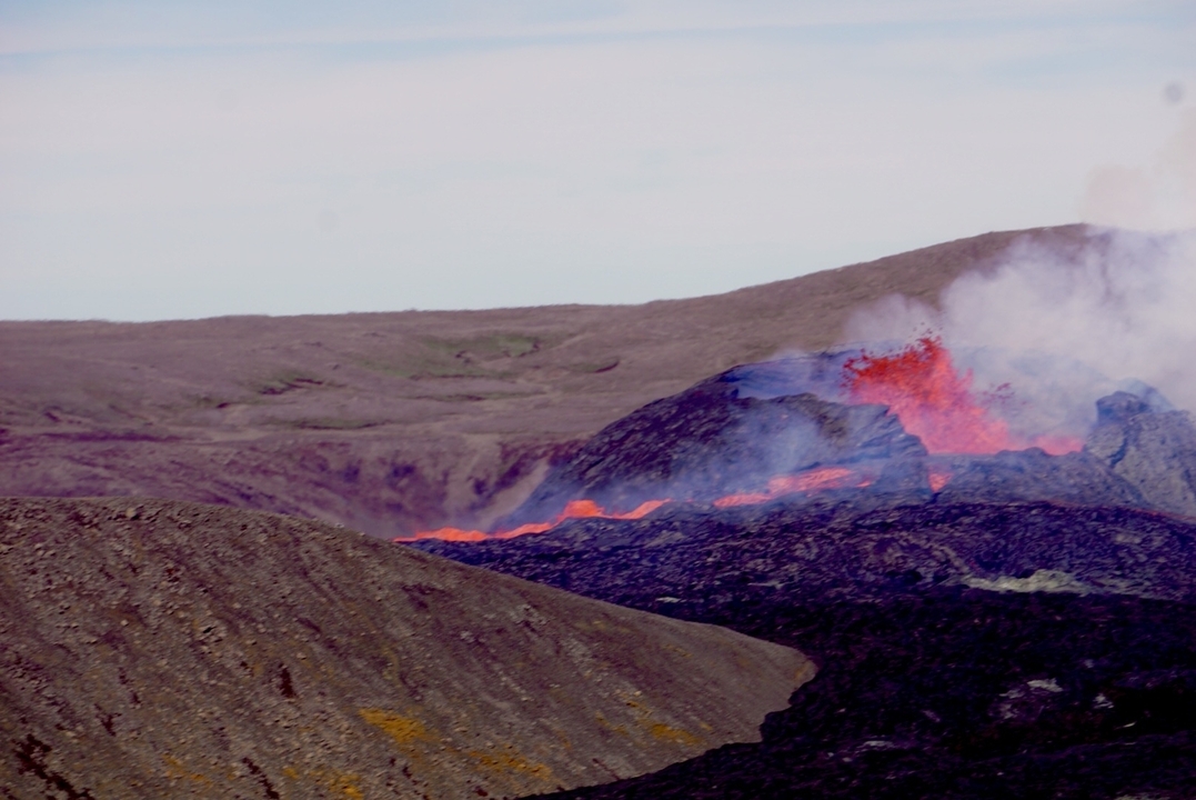 Lava flow with visible red-hot streams in a barren landscape.