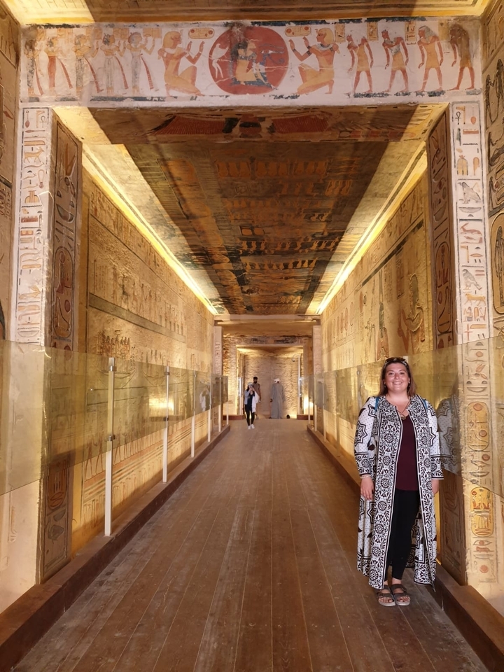 Person standing inside an intricately decorated ancient corridor.