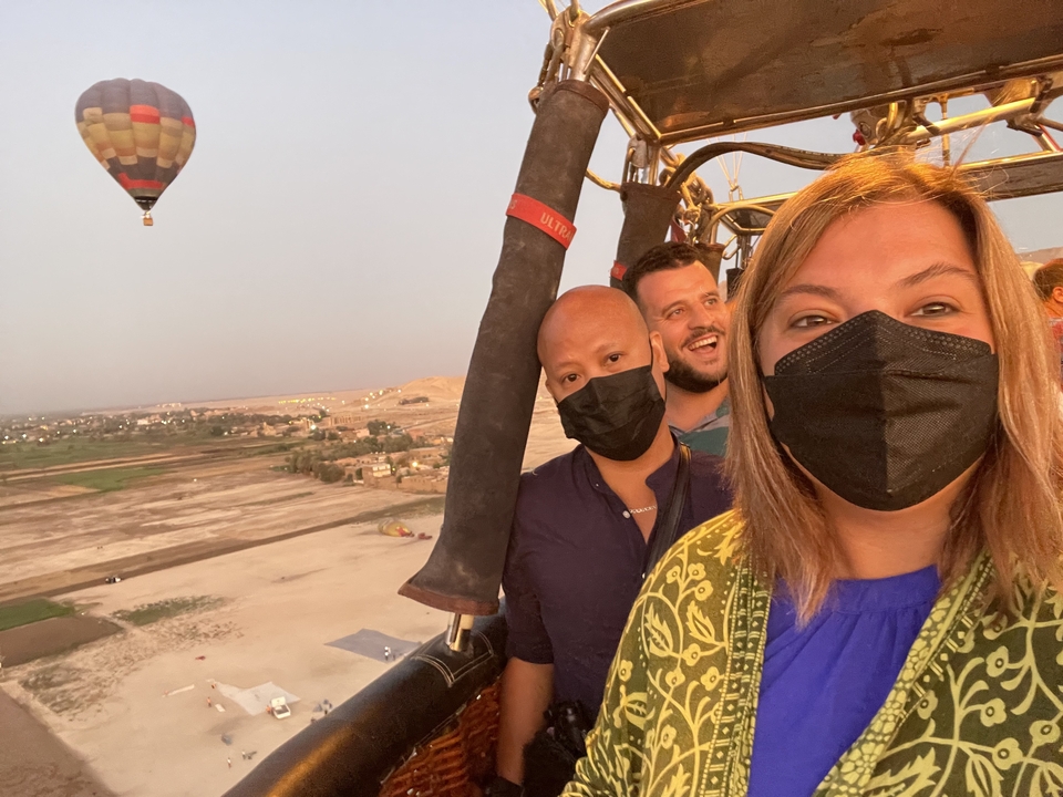 People in a hot air balloon with landscape view.