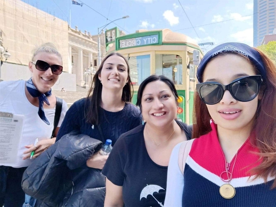 Group of women taking a selfie with a tram in the background.