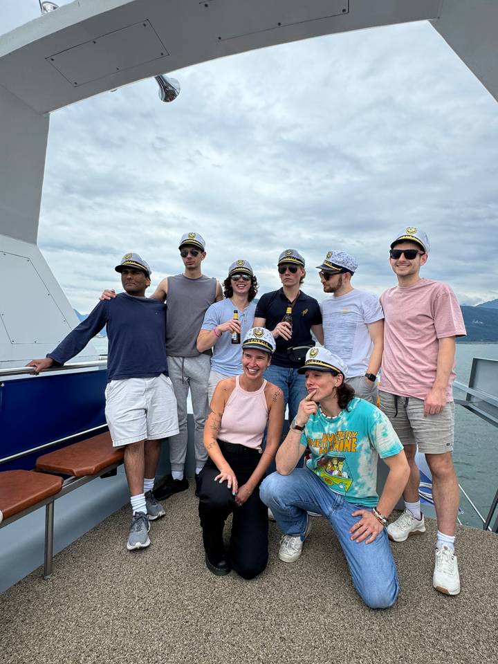 Group of eight people wearing captain hats posing on a ship.