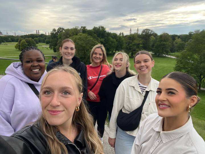 Group of seven women posing in a park setting.