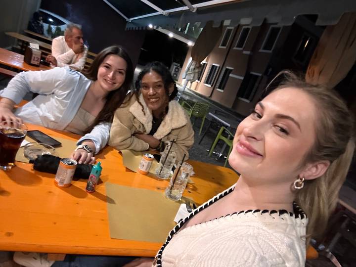 Three friends with drinks at a casual outdoor setting.