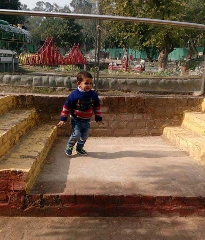 Enfant jouant sur des marches dans un espace extérieur ensoleillé.
