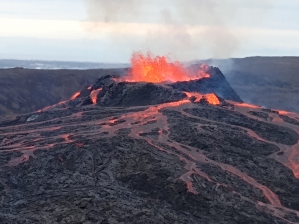 An active volcano erupting with visible lava flows and smoke.