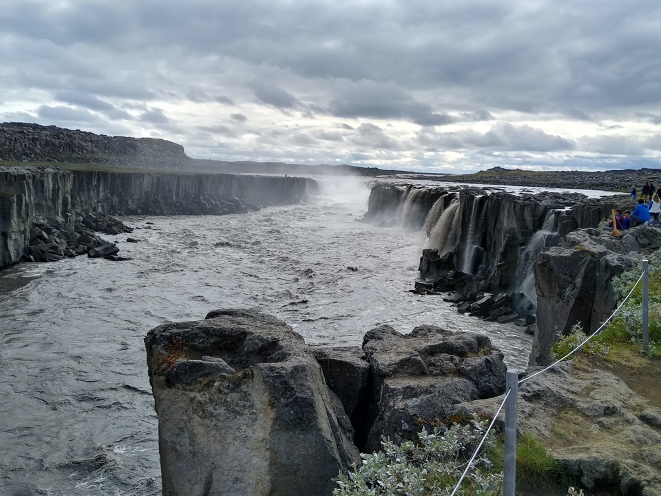A dramatic waterfall with steep rock formations and mist.