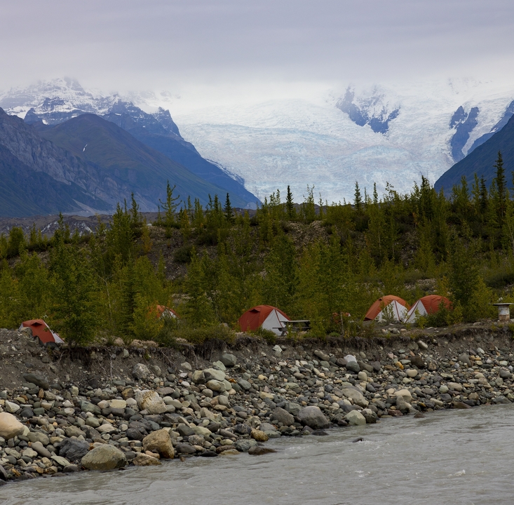 Campsite with tents in front of snowy mountains.