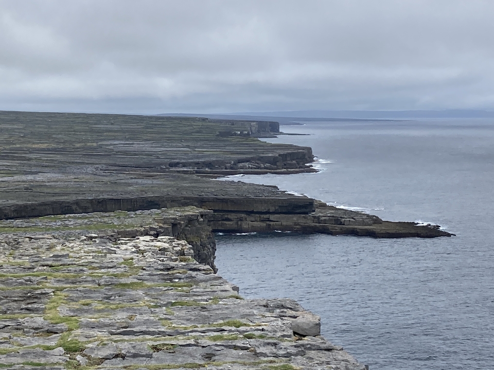Rocky coastline with cliffs and cloudy sky.