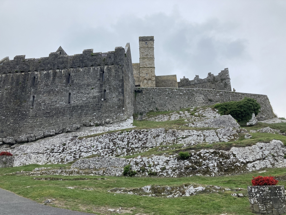 Stone fortress on a rocky hill with cloudy sky.
