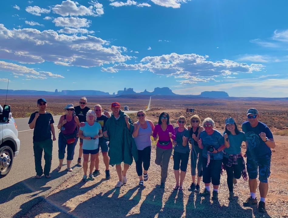 A group of tourists posing in front of a desert landscape.