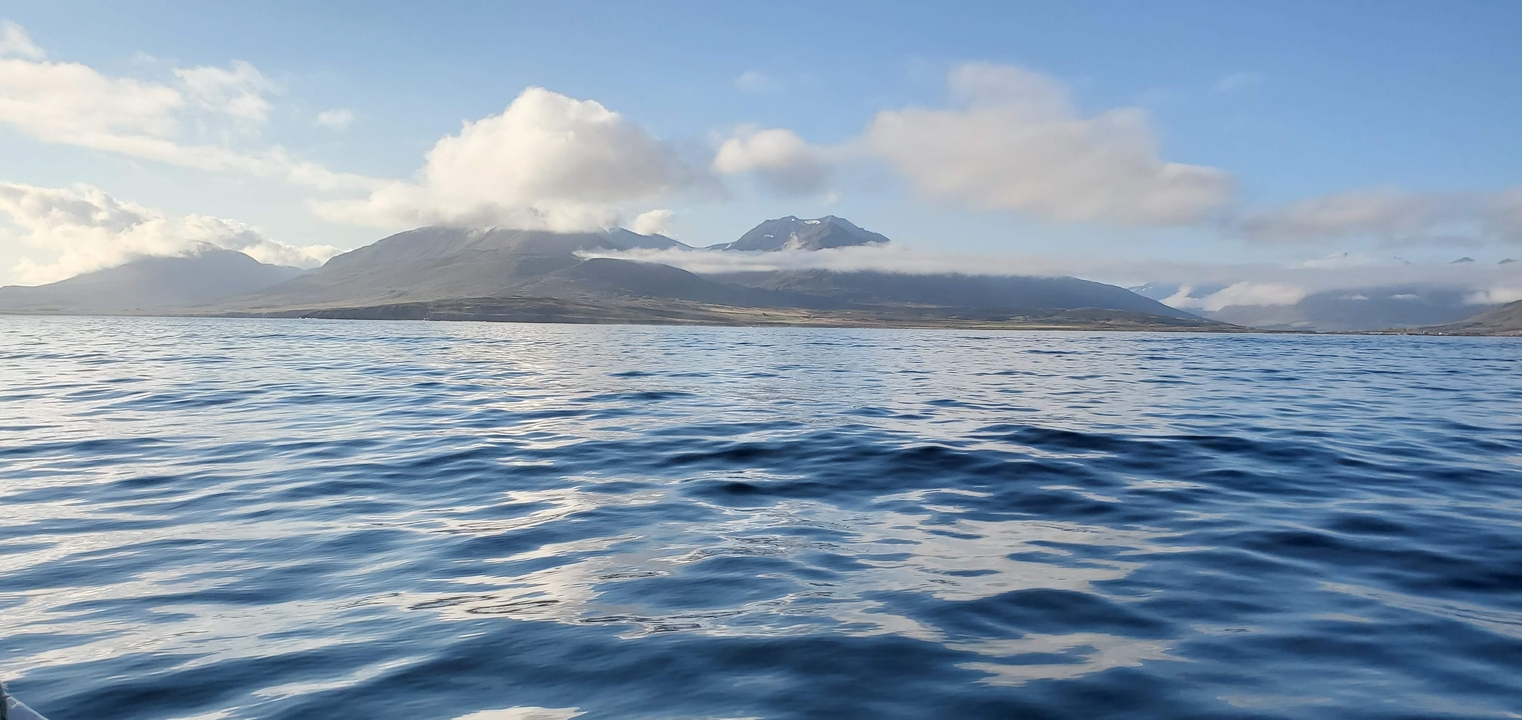 Mountain view over a calm body of water with clouds.