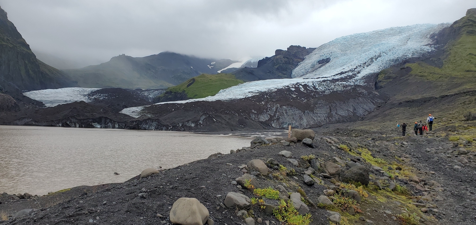Glacier landscape with rocky terrain and hikers.