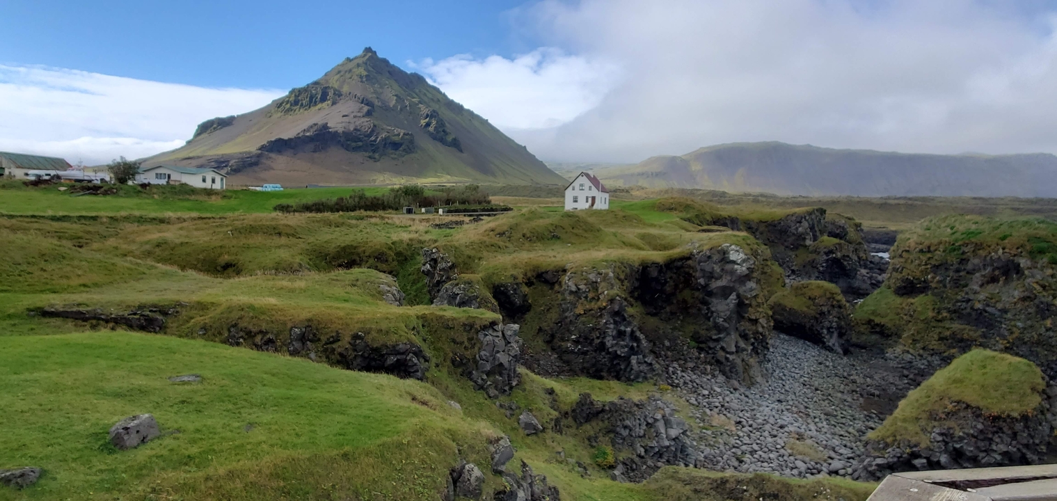 Sharp mountain peak rising above green hills.
