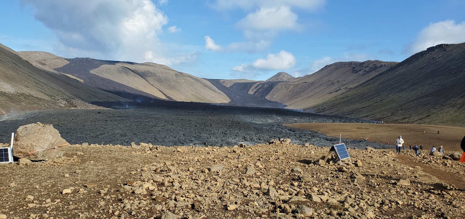 Volcanic crater and expansive rocky terrain under a blue sky.