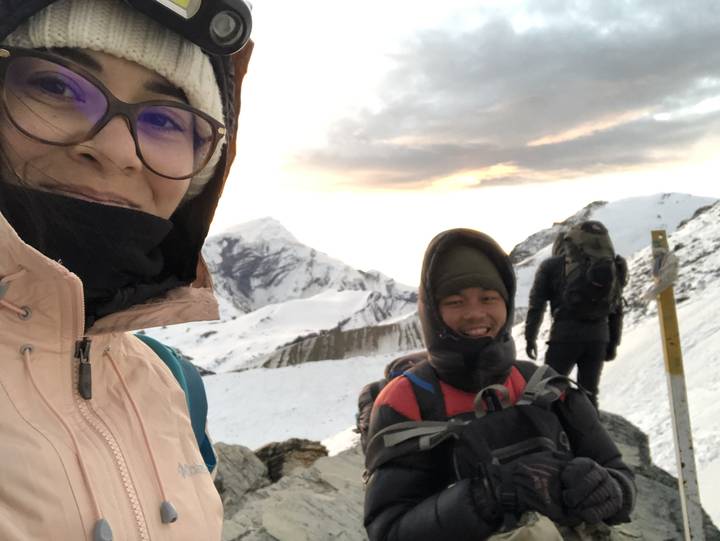 Des gens qui posent dans un terrain montagneux enneigé.