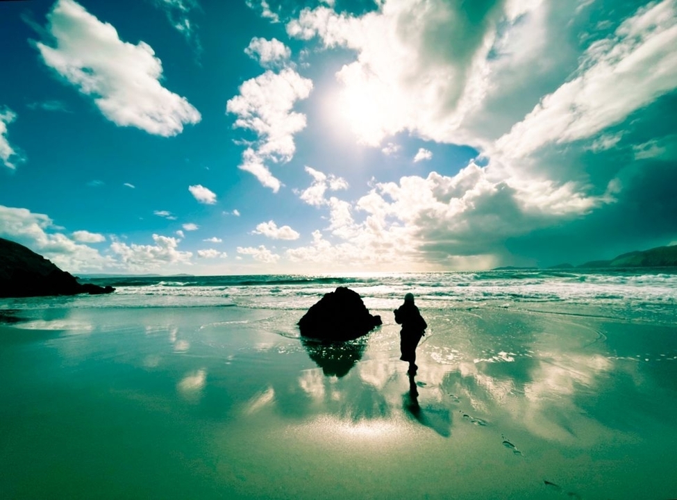 Personne marchant sur une plage pittoresque avec des reflets.