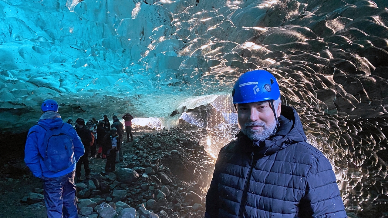 A person in an ice cave with intricate ice formations.