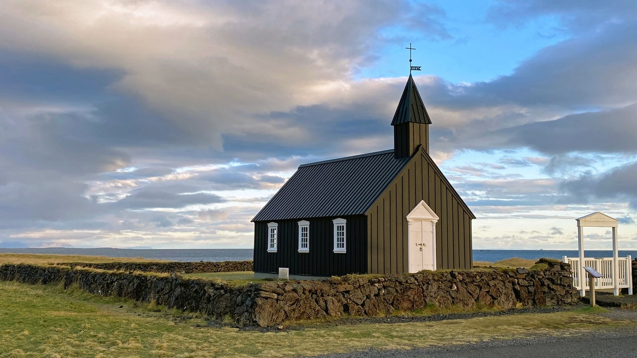 A small black church with a mountainous backdrop.