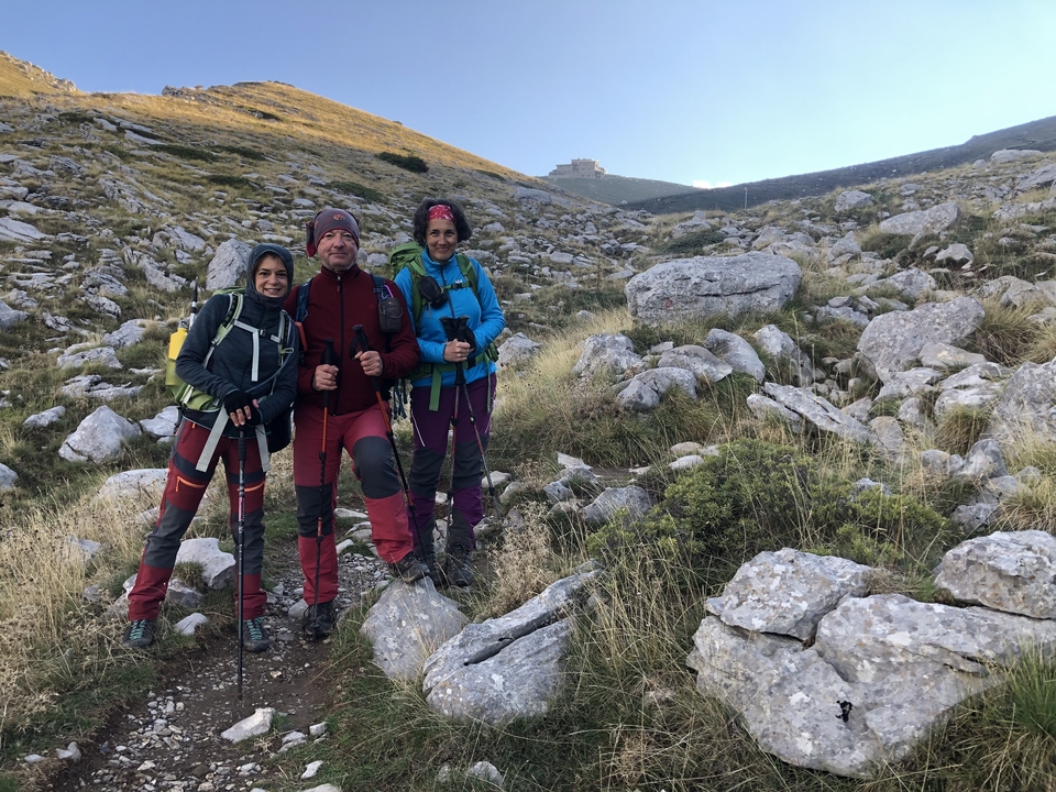Three people dressed for hiking on a rocky trail.