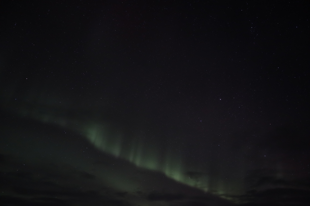 Faibles aurores boréales dans le ciel nocturne.