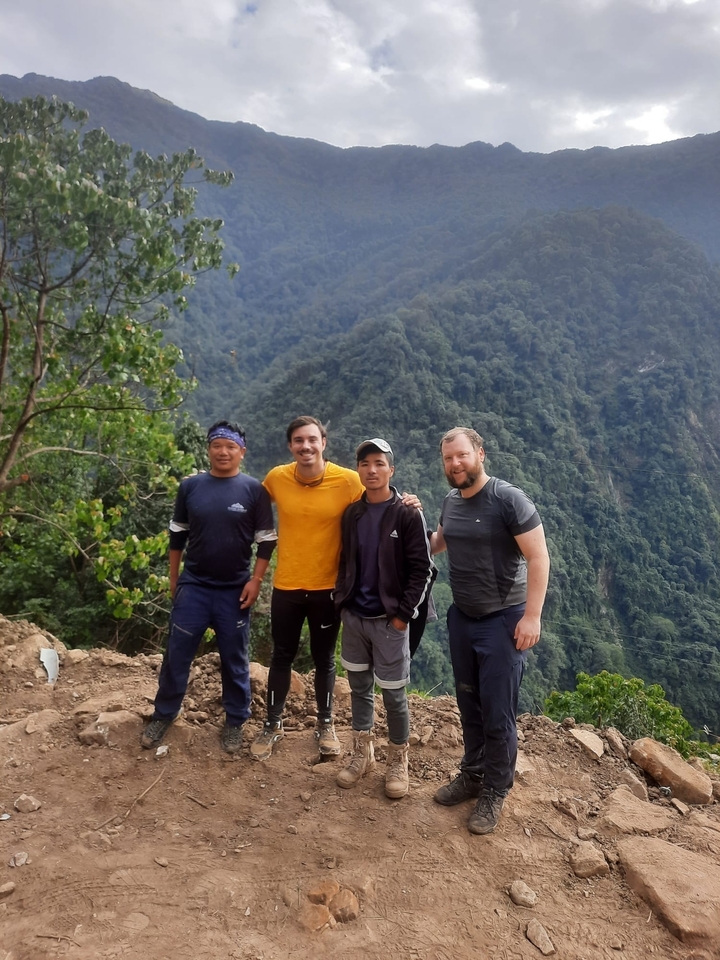 Quatre personnes debout sur une colline avec un arrière-plan verdoyant luxuriant.