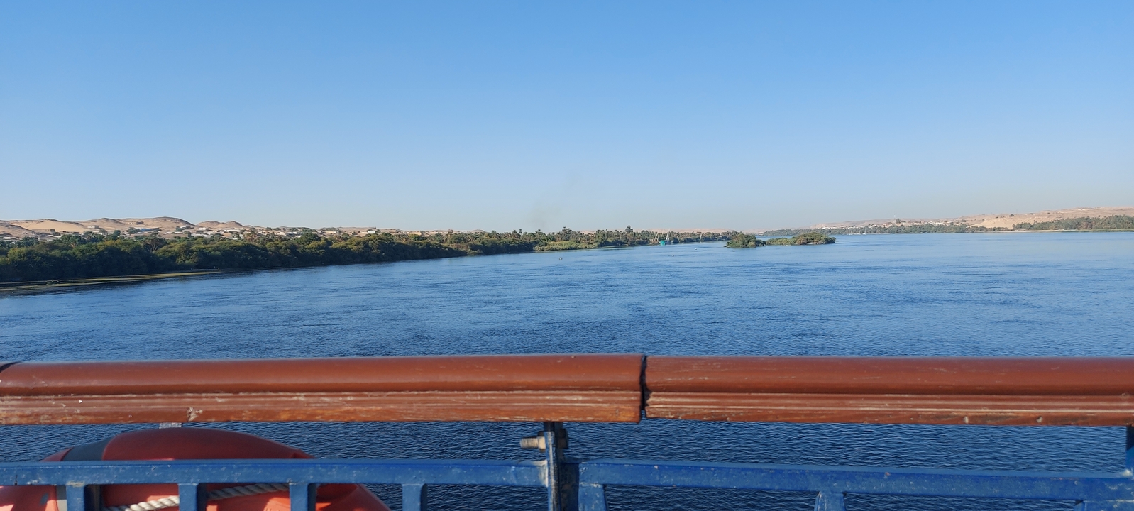 View of a wide river with clear skies and distant greenery.