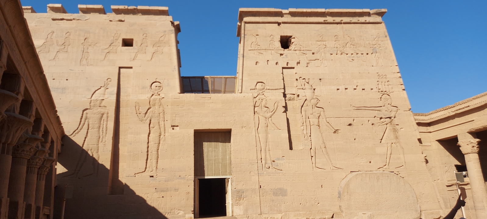 Ancient temple walls with detailed carvings, visited by tourists.