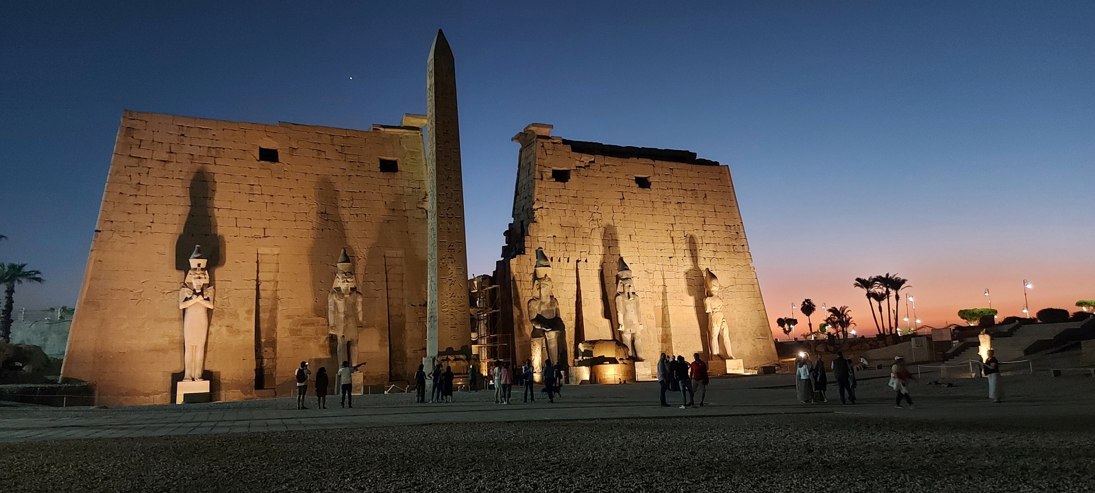 Twilight view of a well-lit ancient temple with visitors.