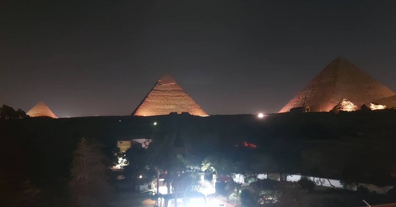 Night view of three illuminated pyramids with a dark sky.