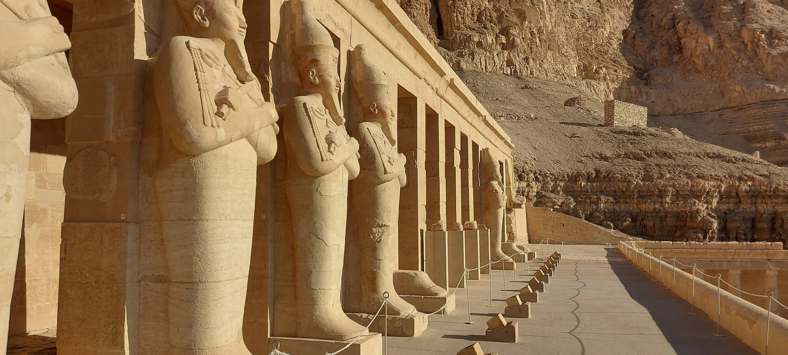 Row of ancient statues in front of a temple carved into rock.