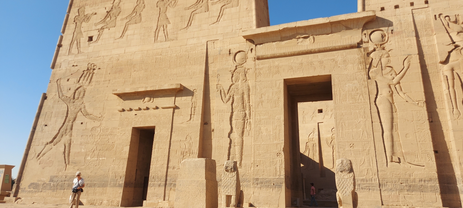 Detailed carvings on an ancient temple with visitors.