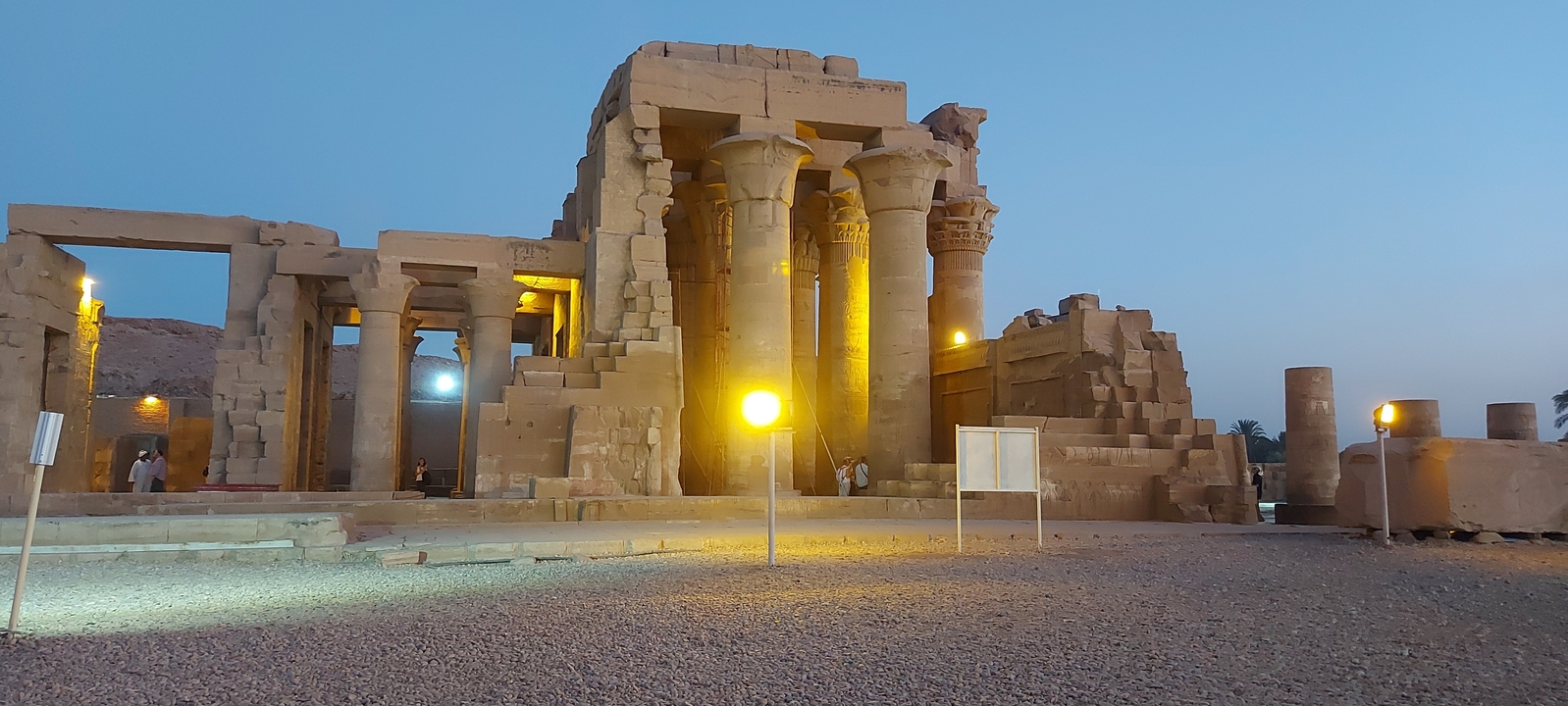 Illuminated temple at night with people exploring the site.