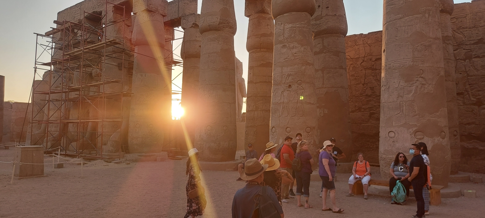 Temple ruins with sunlight casting shadows and people exploring.