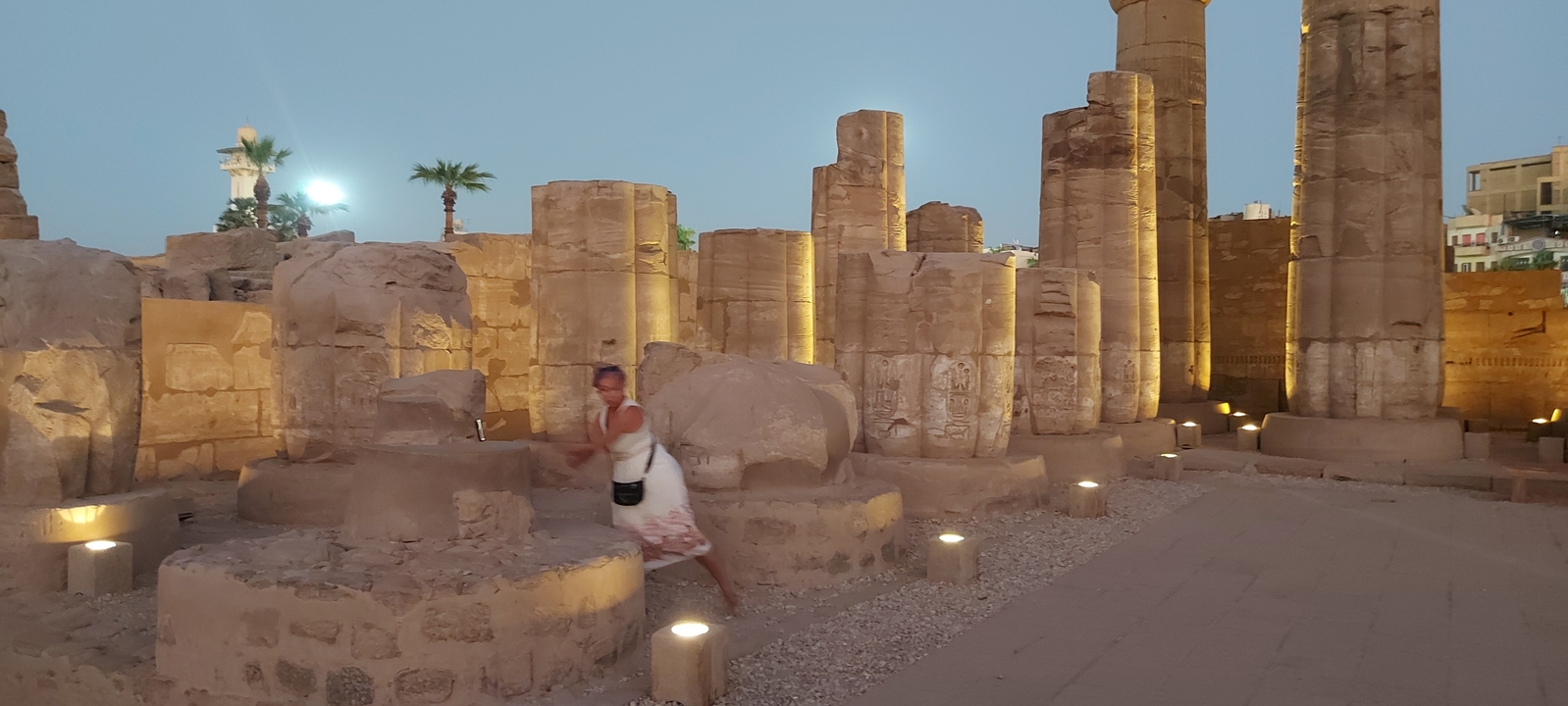 Person walking through illuminated ancient ruins at dusk.