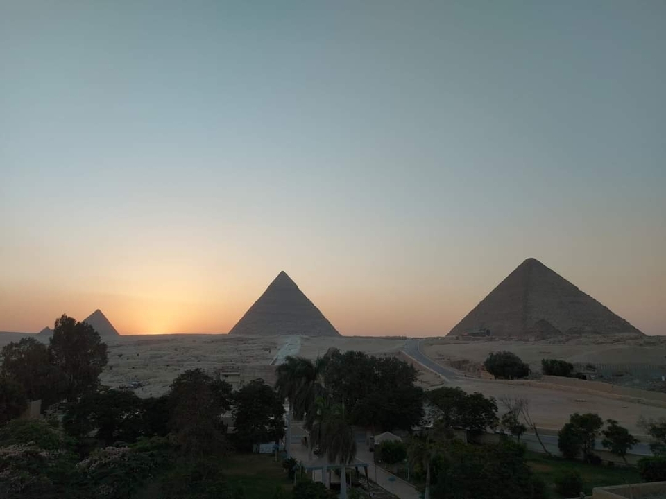Sunset view of three pyramids with a clear sky.