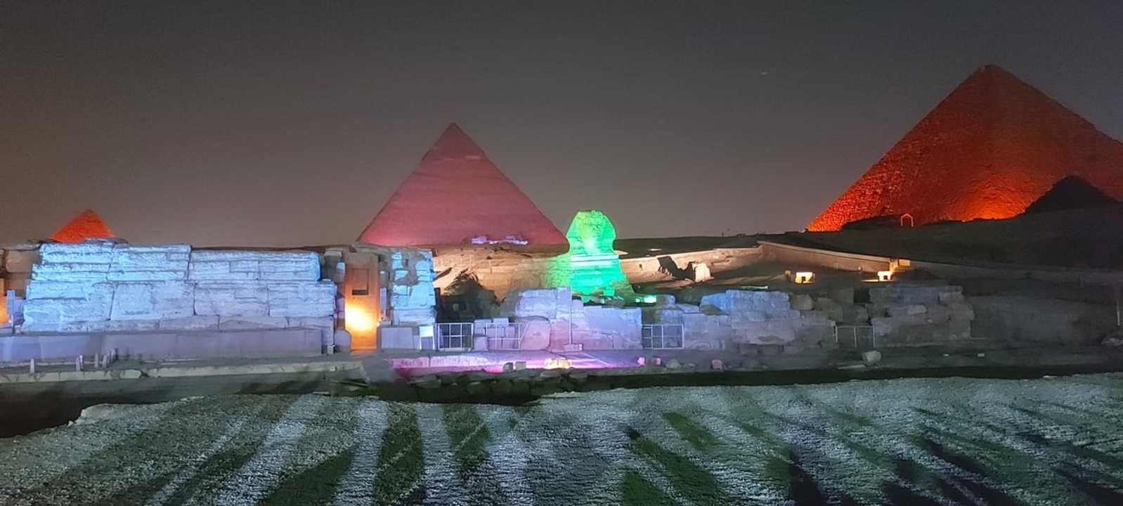 Colorful light show at the Pyramids of Giza and Sphinx at night.